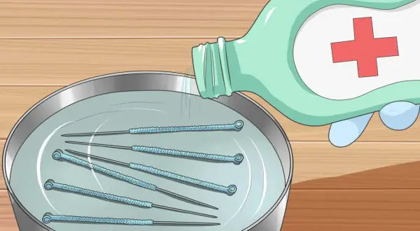 Pour du liquide désinfectant sur des aiguilles dans un bol pour comment stériliser une aiguille.