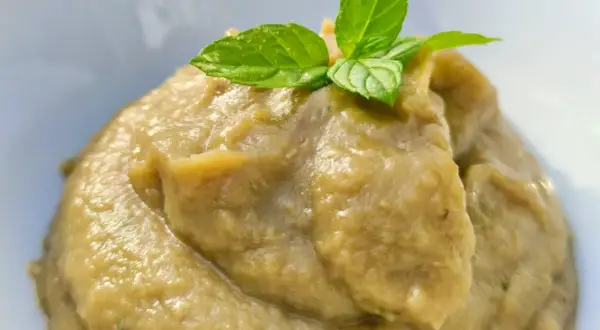 Patè di melanzane cremoso, perfetto per crostini, guarnito con foglie di menta fresca.