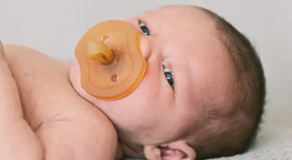 Neugeborenes Baby mit Schnuller. Die Frage "ab wann Schnuller?" beschäftigt viele Eltern.