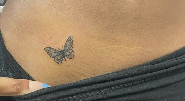 Delikatny tatuaż motyla na skórze, w miejscu intymnym, symbolizujący wolność i piękno.