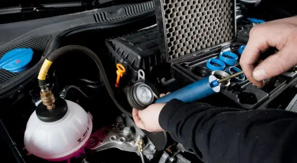 Controllo del radiatore macchina con kit di prova. Un tecnico usa uno strumento per verificare la pressione del sistema di raffreddamento.
