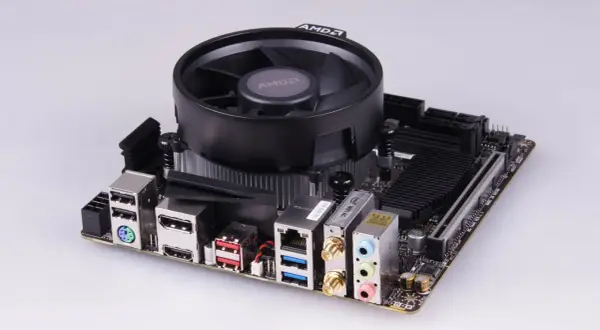Mainboard mit AMD-Kühler, bereit für einen Ryzen 5 2400G Prozessor. Anschlüsse für USB, HDMI, LAN und Audio sind sichtbar.