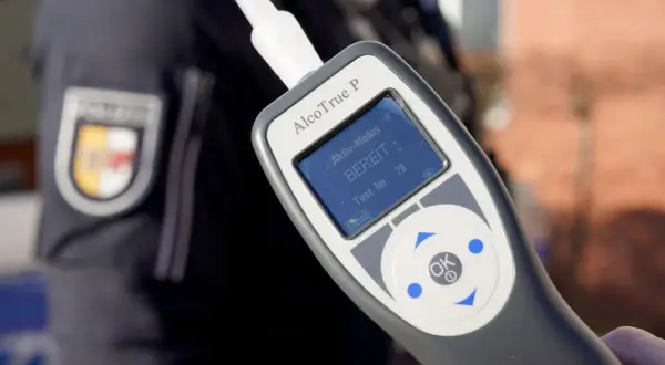 Polizist hält Alkoholtester. Das Gerät zeigt "BEREIT" an. Eine promille alkohol tabelle hilft, die Werte zu verstehen.
