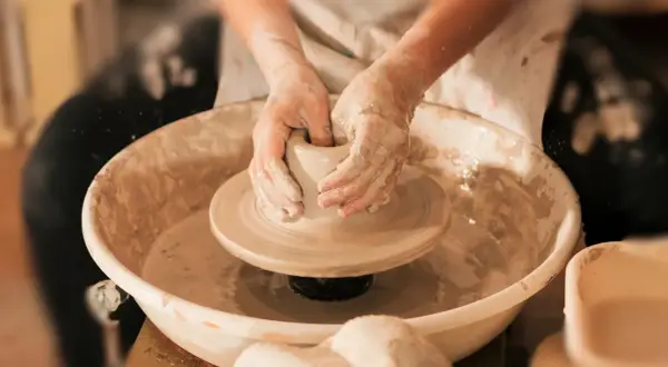 Mani esperte modellano l'argilla su un tornio, creando un pezzo unico di artigianato locale.