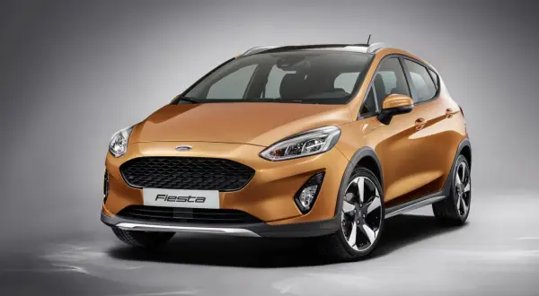 Pomarańczowy Ford Fiesta MK9 z czarnymi akcentami i relingami dachowymi, gotowy na miejskie przygody.