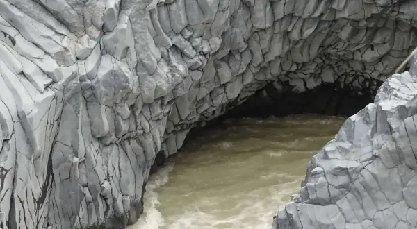 Die Alcantara Schlucht in Sizilien zeigt faszinierende Basaltsäulen, die von einem türkisfarbenen Fluss umspült werden.