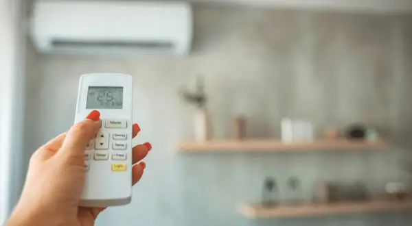 Main tenant ajuste la température de la climatisation pour un confort optimal, gérant la température clim été.
