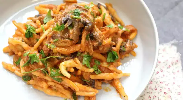 En krämig pasta boscaiola med svamp och persilja, serverad i en vit skål.