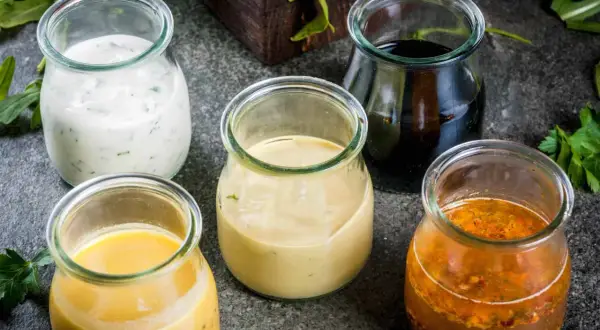 Fem burkar med olika dressingar, från krämig vit till mörk balsamico. Vilken är godaste dressingen till sallad?