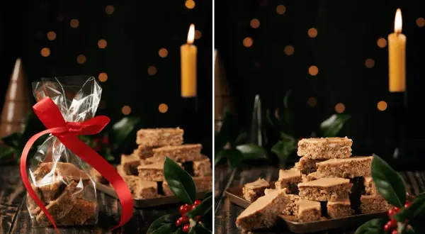Weihnachtliche Elisenlebkuchen vom Blech, liebevoll verpackt und auf einem Blech gestapelt, mit Kerzenlicht und Tannenzweigen.