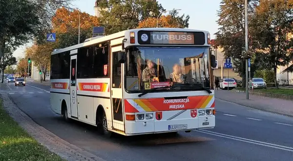 Autobus komunikacji miejskiej z napisem "TURBUSS" na tablicy kierunku, na ulicy w jesienny dzień. Rejestracja ELU.