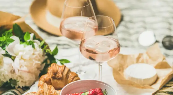 Zwei Gläser mit erfrischenden rose Weine, dazu Croissants, Erdbeeren und Käse. Ein perfektes Picknick!