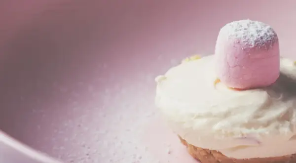 Delizioso namelaka al cioccolato bianco, con una soffice nuvola rosa in cima, adagiato su un piatto rosa cipria.