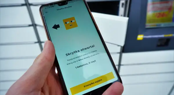 Dłoń trzyma smartfon z aplikacją InPost informującą o otwartej skrytce.