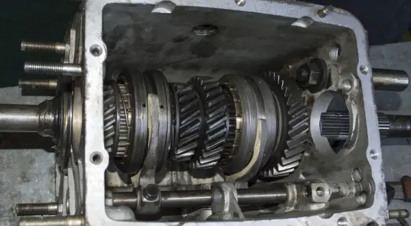 Vue détaillée d'une boîte de vitesses ouverte, montrant les engrenages et les synchroniseurs. Le mécanisme de synchro boite de vitesse est visible.