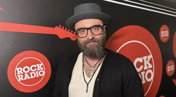 Mężczyzna w kapeluszu i okularach, z brodą, na tle logo Rock Radia. Widać napis "perfect wszystko ma swój czas tekst".