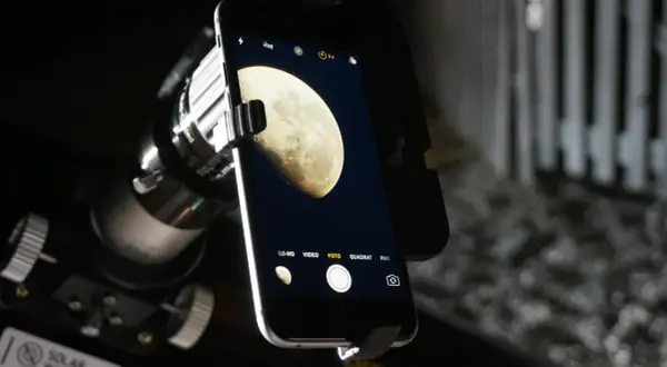 Telefon z aparatem uchwycił zdjęcie księżyca w pełni, widocznego przez teleskop.