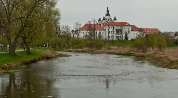 Malowniczy widok na Supraśl z rzeką w tle i klasztorem. Wiosna w pełni, zielone drzewa i krzewy.