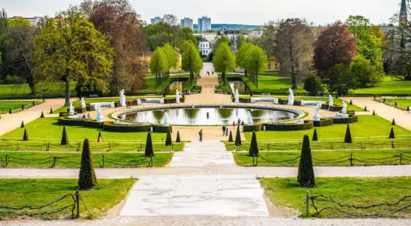 Ein prächtiger Park mit einem runden Teich, Statuen und gepflegten Rasenflächen. Ein ideales Motiv für Ausflugsziele Potsdam.