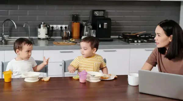 Mama słucha, kiedy chłopcy zaczynają mówić, jedząc śniadanie w kuchni.