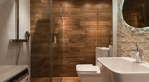 Moderno baño con ducha de cristal, paredes de madera y lavabo. ¿Cuánto cuesta cambiar bañera por plato de ducha?