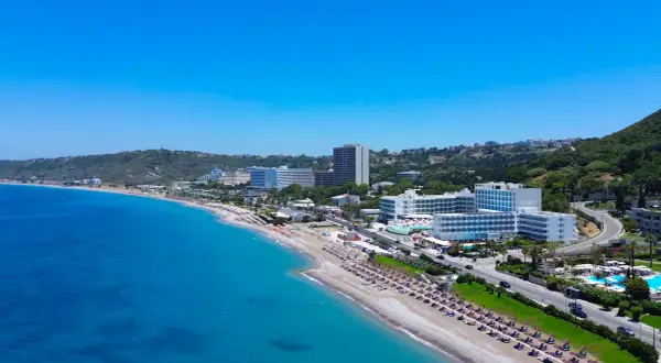 Piękna plaża w Ixia, Rodos, z turkusowym morzem i hotelami w tle.