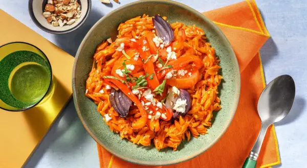 En skål med orzopasta med rostade grönsaker, fetaost och mandlar. Ett perfekt basilika recept för en snabb middag.