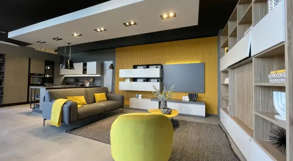 Un soggiorno moderno con divano grigio, cuscini e coperta senape colore, poltrona gialla vivace e parete di fondo color ocra.