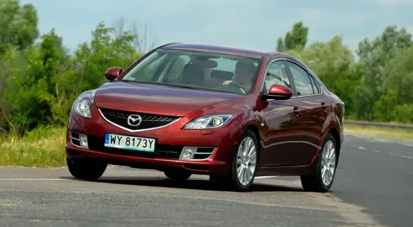 Czerwona Mazda 6 2.0 benzyna jedzie po drodze, za kierownicą siedzi mężczyzna.