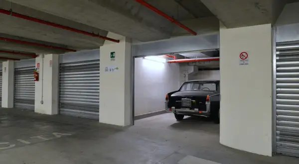 Un'auto d'epoca nera in un garage sotterraneo. Le porte a serranda chiuse e l'illuminazione suggeriscono che affittare garage conviene per proteggere il tuo veicolo.
