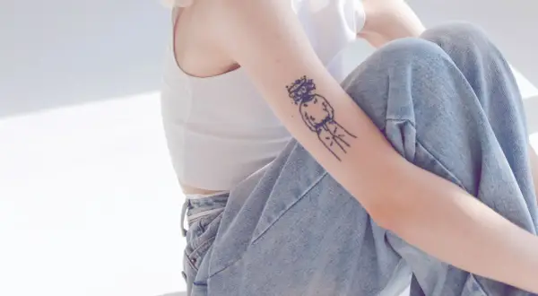 Ein Arm mit einem abstrakten Tattoo, das eine Figur mit Krone zeigt. Ein Beispiel für beste Tattoos, die Persönlichkeit ausdrücken.