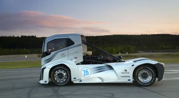 Le camion de course "The Iron Knight" blanc et argenté, numéro 26, sur une piste au coucher du soleil.