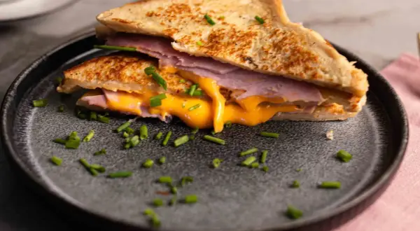 Herzhaftes French Toast mit Schinken und geschmolzenem Käse, garniert mit Schnittlauch.