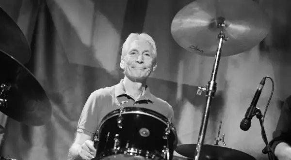 Charlie Watts, perkusista Rolling Stones, uśmiecha się za swoim zestawem perkusyjnym.