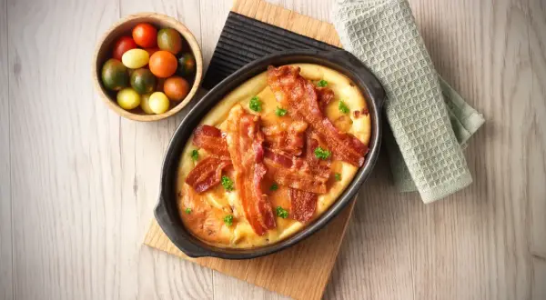 En härlig ugnspannkaka med knaprigt bacon och färska örter, serverad med en skål körsbärstomater.