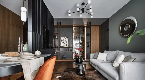 Eleganckie aranżacje nowoczesny salon: szara sofa, pomarańczowy fotel, drewniana podłoga i designerskie oświetlenie tworzą przytulną przestrzeń.