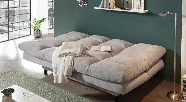Gemütliches Schlafsofa im Wohnzimmer, ideal zum dauerhaft im wohnzimmer schlafen. Mit Decke und Buch für entspannte Stunden.