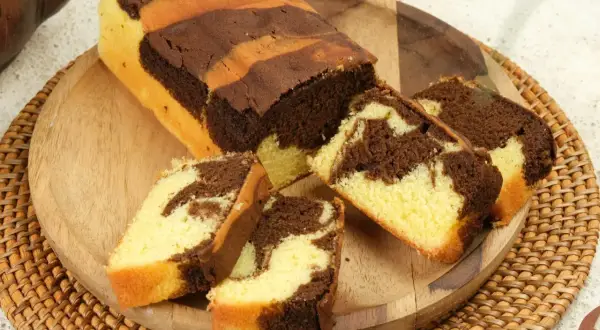 Babka marmurkowa z czekoladą i wanilią, pokrojona na plastry, na drewnianej desce.