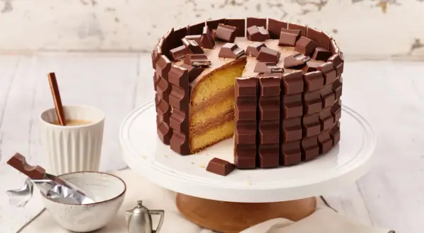 Eine köstliche Kinderriegel Torte, umhüllt von Schokoriegeln und garniert mit Stückchen. Ein Traum für jeden Schokoladenliebhaber!