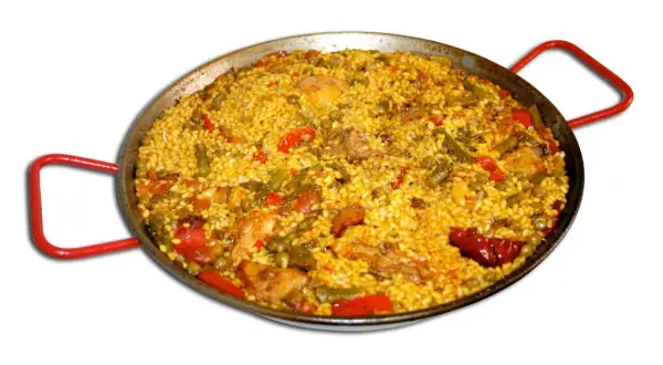 En stor paella med ris, kyckling, gröna bönor och paprika i en traditionell paellapanna med röda handtag.