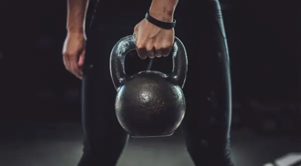 A person's hand grips a kettlebell, ready for a powerful kettlebell boxing workout.