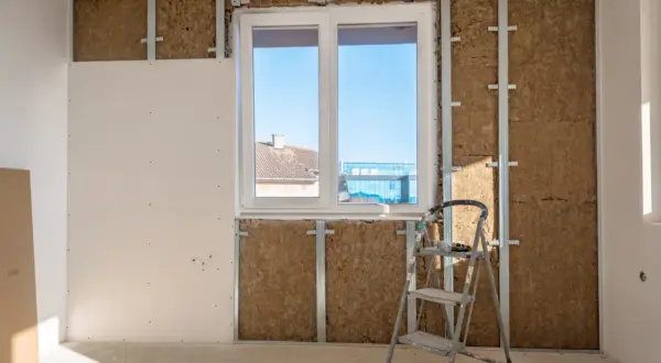 Installazione di sistemi di isolamento termico con lana di roccia e cartongesso, con una scala appoggiata al muro.