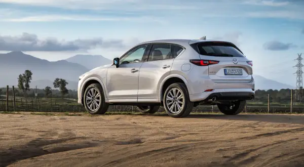 Biała Mazda CX-5 na tle gór i nieba. Elegancki SUV gotowy na przygodę.