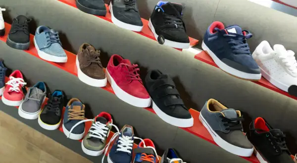 Scaffali pieni di sneakers, tra cui modelli nira rubens, in vari colori e stili, pronte per essere indossate.