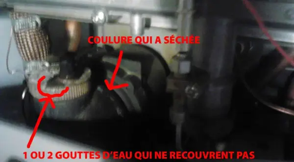 Détail d'une chaudière : une coulure sèche et une petite tache humide près d'un bouchon, peut-être la cause d'une veilleuse chauffage gaz ne tient pas.