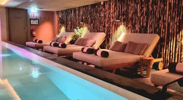 Avslappning vid poolen på ett elite hotell i Borlänge. Bekväma solstolar med kuddar och handdukar står redo vid det upplysta vattnet.