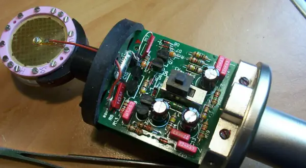 Elementy budowy mikrofonu: płytka drukowana z elementami elektronicznymi, kapsuła z membraną i pęseta.