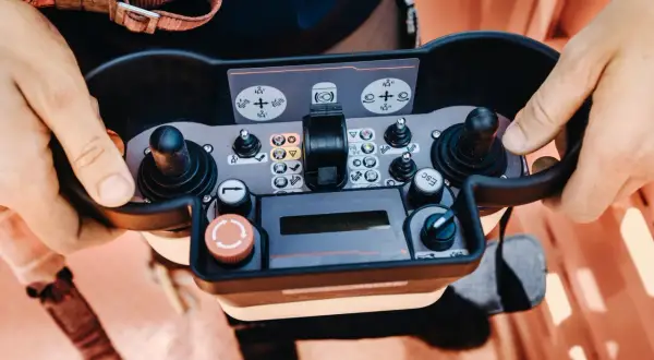 Operator próbuje sterować maszyną, ale brama nie reaguje na pilota. Widoczne przyciski i joysticki panelu sterowania.
