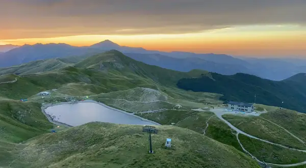 Alba sulle montagne toscane, con un lago alpino e rifugi che ricordano i borghi vicino Abetone.
