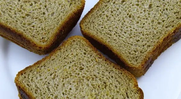 Trzy kromki chleba orkiszowego na białym talerzu. Czy mąka orkiszowa ma gluten? Tak, orkisz zawiera gluten.